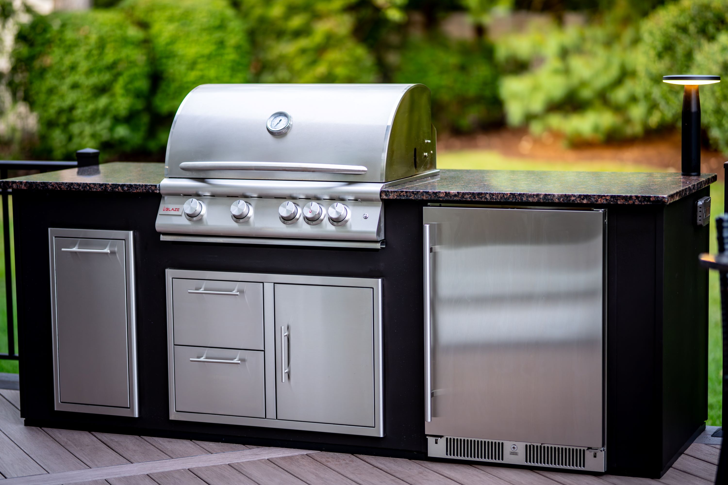 outdoor kitchen with built-in grill, refrigerator, granite countertops, and storage cabinets on deck